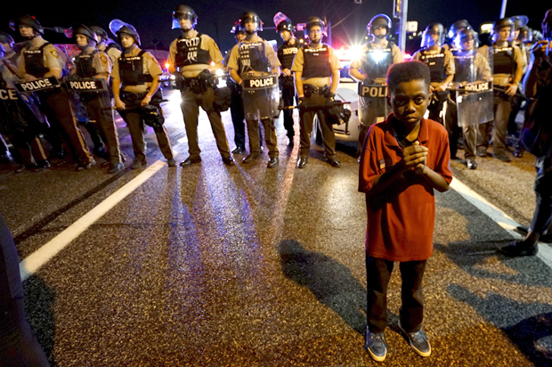 Amarion Allen, 11-years-old, stands in front of a police line shortly before shots were fired in a police-officer involved shooting in Ferguson, Missouri August 9, 2015. Two people were shot in the midst of a late-night confrontation between riot police and protesters, after a day of peaceful events commemorating the fatal shooting of Michael Brown by a white officer one year ago.  REUTERS/Rick Wilking      TPX IMAGES OF THE DAY      - RTX1NPTC